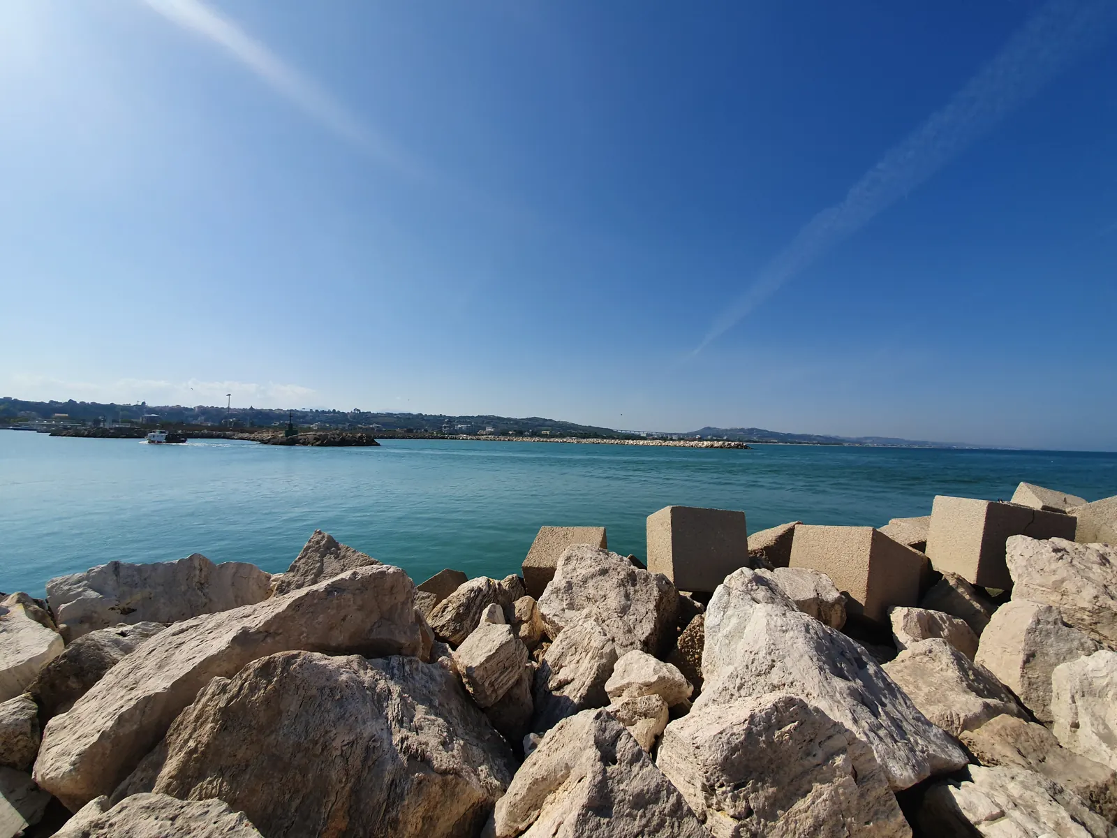 Clear harbour water beside a rocky breakwater in daylight