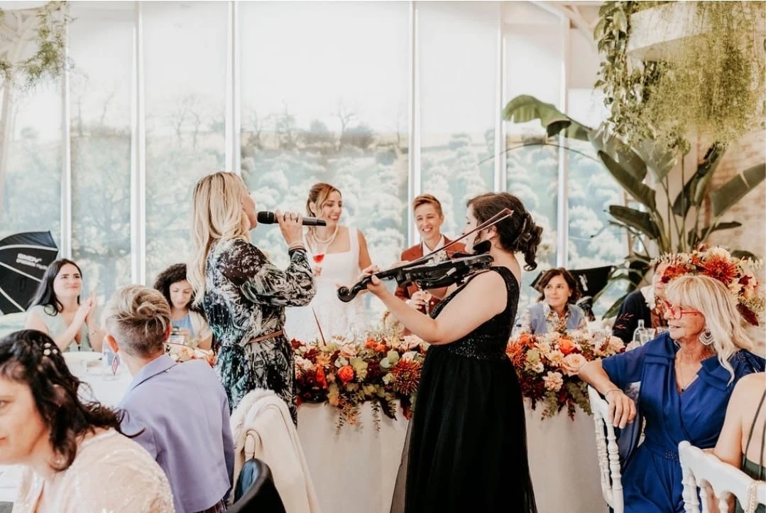 A singer and violinist performing at the reception, with Claudia and Bruna behind them