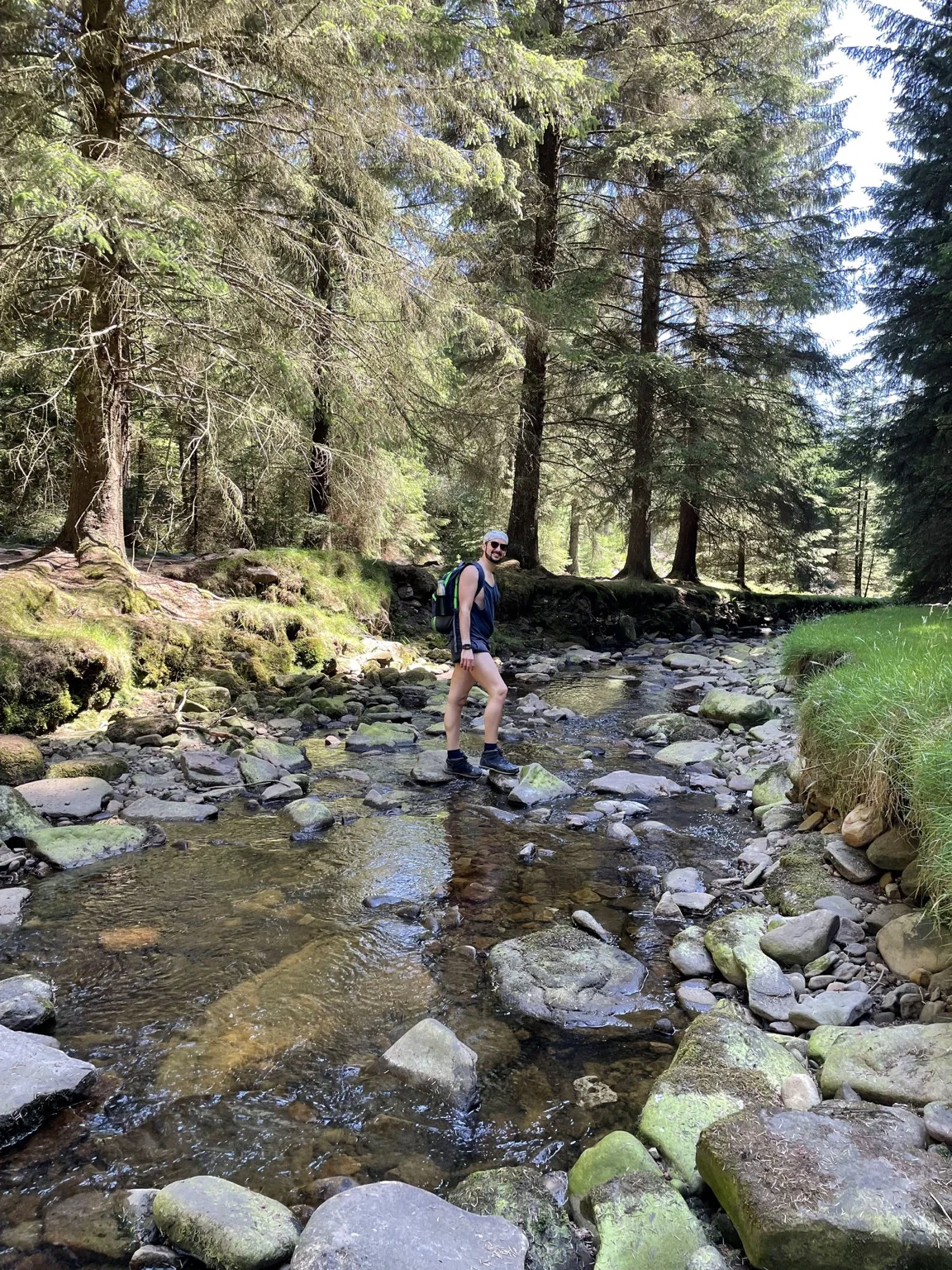 Daniele standing on stepping stones in a woodland stream.