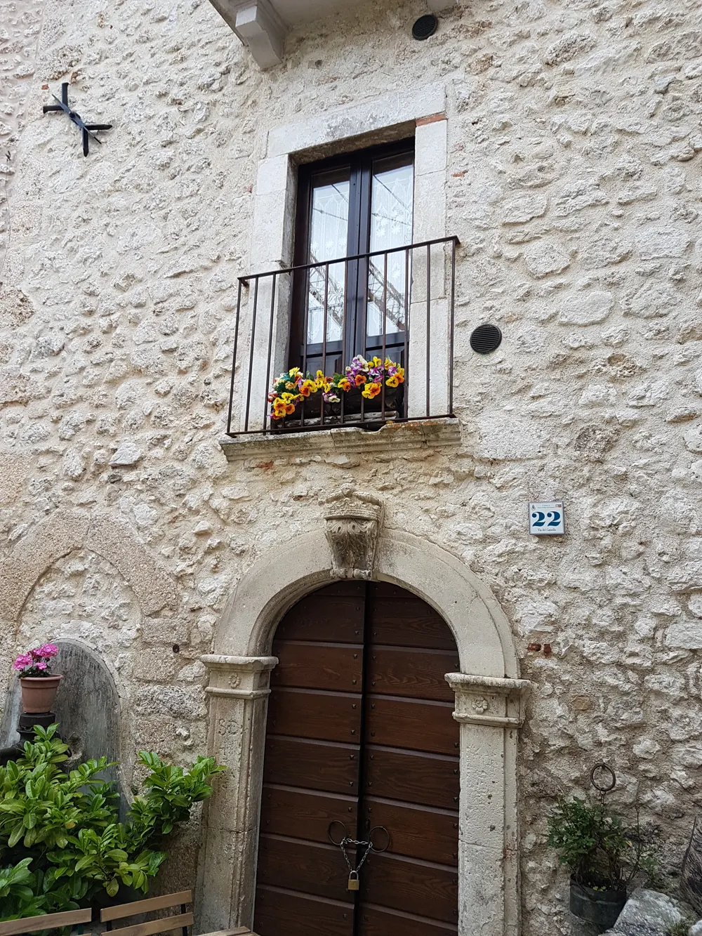 A stone doorway and flower-filled balcony in Santo Stefano di Sessanio
