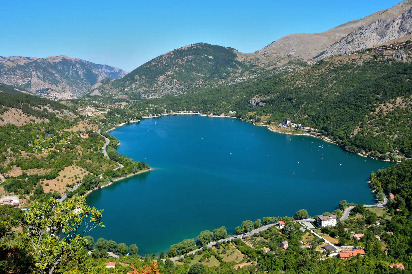 Elevated view of Lago di Scanno with its heart-shaped outline framed by wooded mountains
